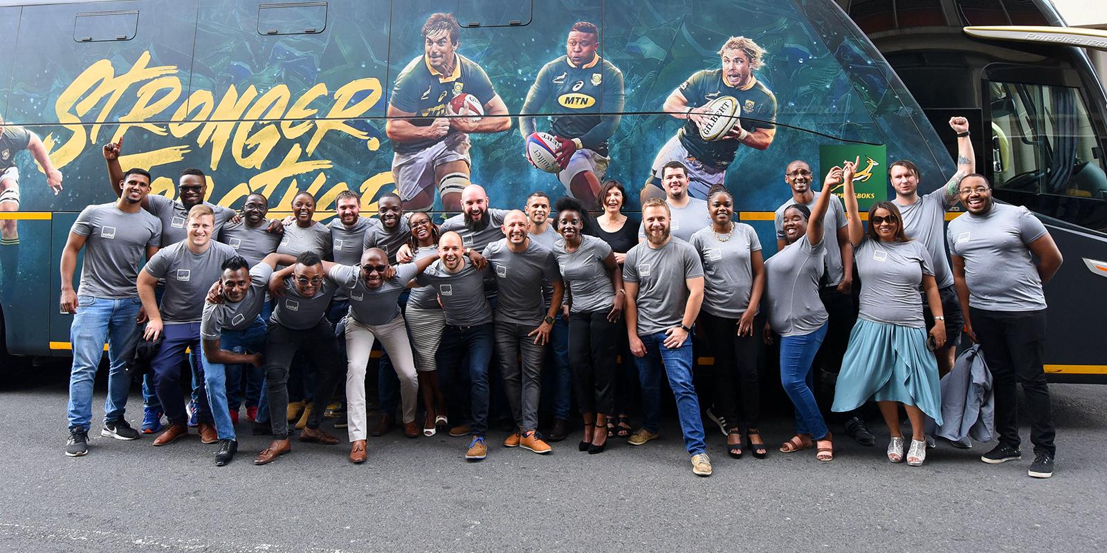 The Solid Systems team cheering together in front of the Springboks' Stronger Together bus