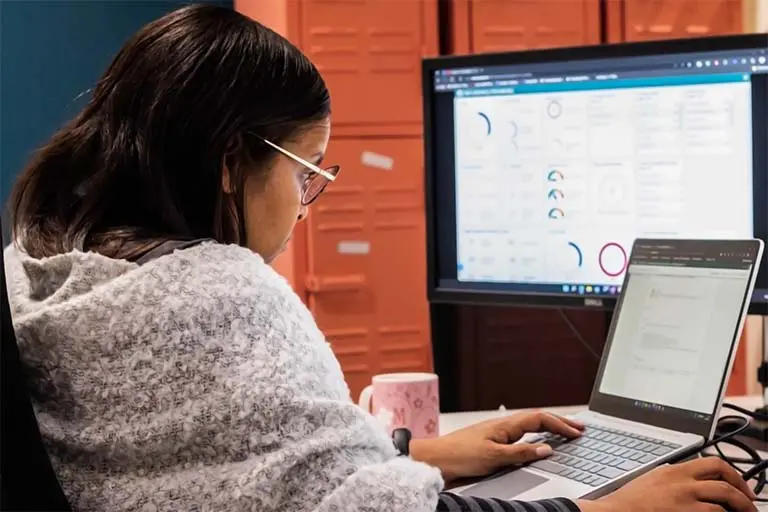 A Solid Systems engineer working on a laptop beside a cloud dashboard