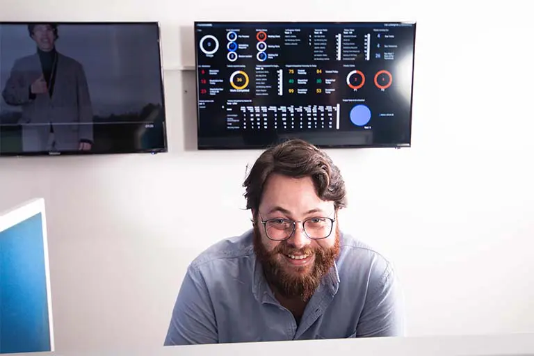 A smiling Solid Systems IT Pro in front of the live service dashboards