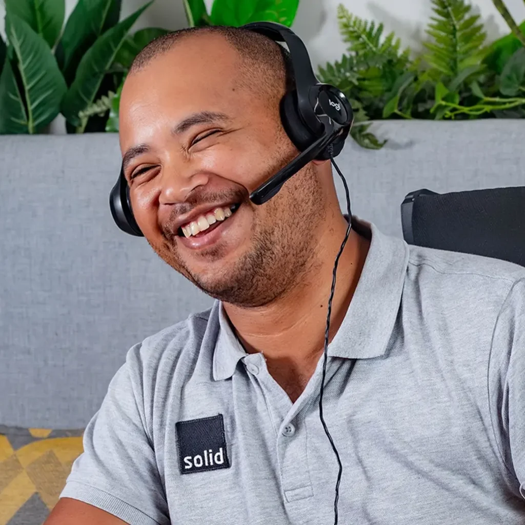 A Solid Systems IT Pro laughing on a support call, wearing a headset