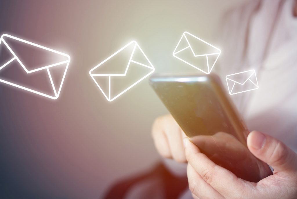 Glowing email envelopes flying out of a smartphone held in two hands